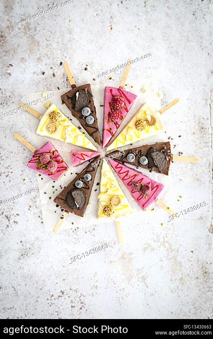 Three different types of cheesecake slices on sticks