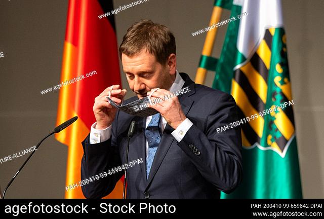 09 April 2020, Saxony, Dresden: Michael Kretschmer (CDU), Prime Minister of Saxony, puts on a face mask after his speech during a special session of the Saxon...