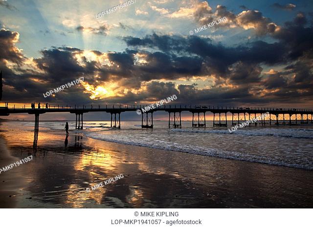 England, Redcar & Cleveland, Saltburn-By-The-Sea. Rays of sunlight from the setting sun over the Victorian pier at Saltburn-By-The-Sea