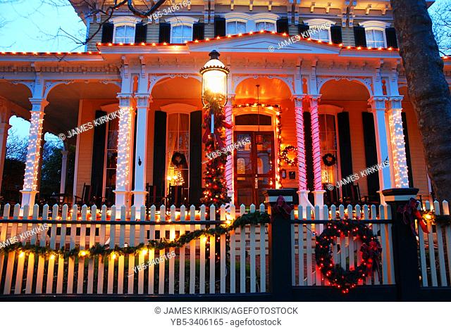 A grand Victorian home is decorated with Christmas lights