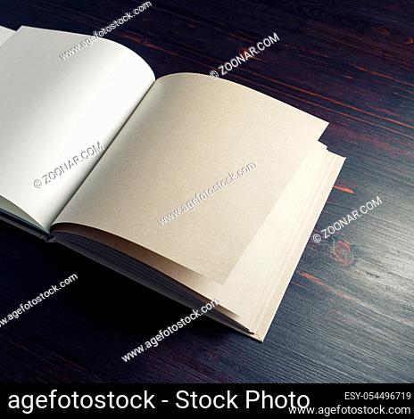 Open blank kraft paper book or sketchbook on wood table background. Branding mock up. Copy space for text