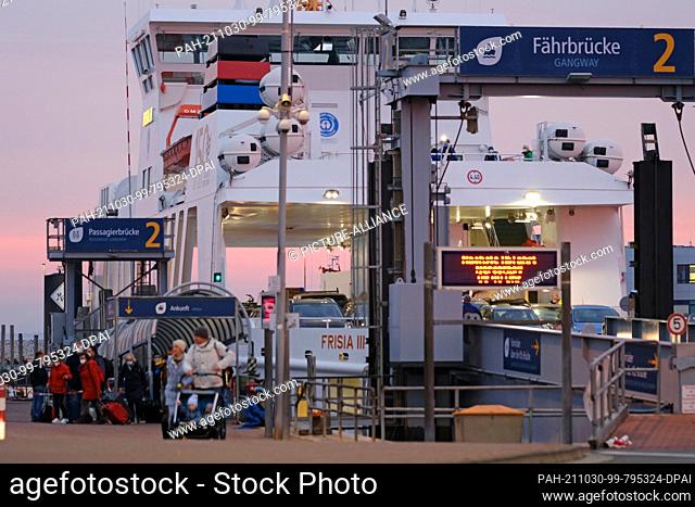 30 October 2021, Lower Saxony, Norddeich: People leave the ferry that arrived from Norderney early on Saturday morning and board a shuttle bus at the port in...
