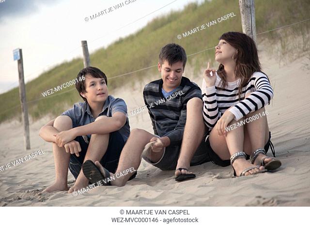 Netherlands, three teenagers relaxing on the beach
