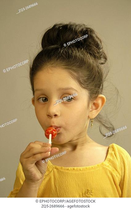 A green eyed girl licking a lollypop