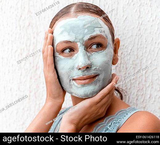 Closeup Portrait of a Pretty Girl with Cream Mask on her Face Isolated on White Background. Using Clay for Perfect Skin. Beauty Treatment Concept