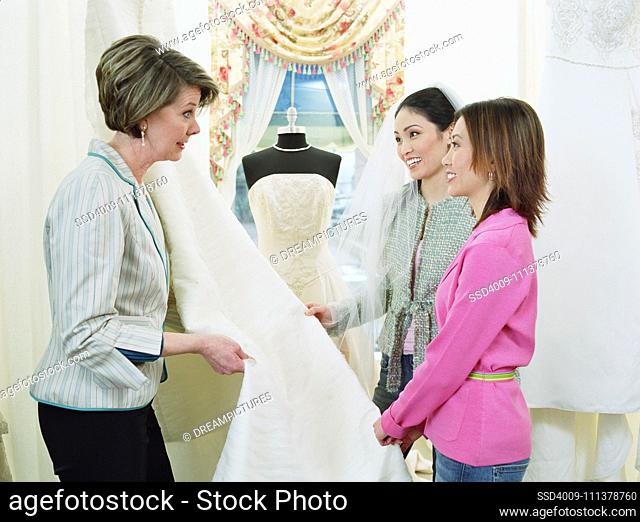 Tailor helping young women pick bridal fabric