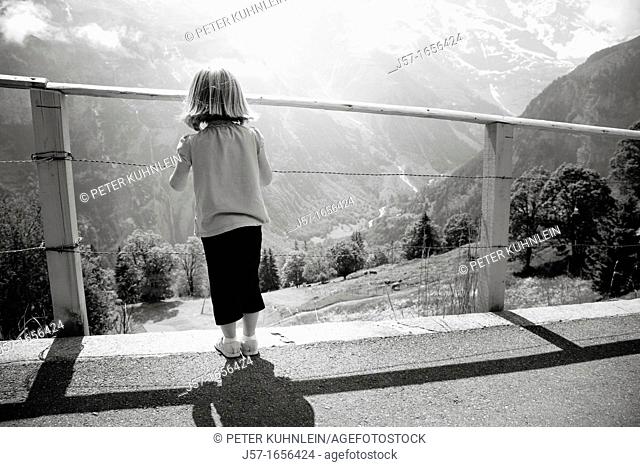 Young girl looking through a fence at a mountain scene in Mürren, Switzerland
