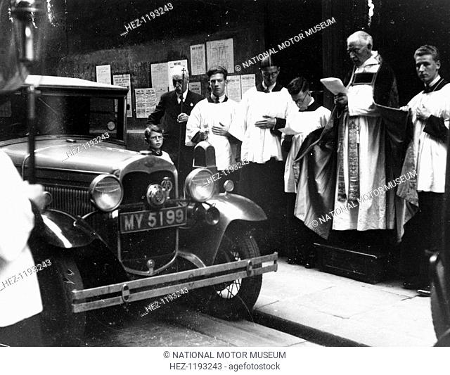 The blessing of cars, City of London, c1930. A priest conducts a blessing in front of a car. The ceremony takes place on July 20th, the feast of St Elias