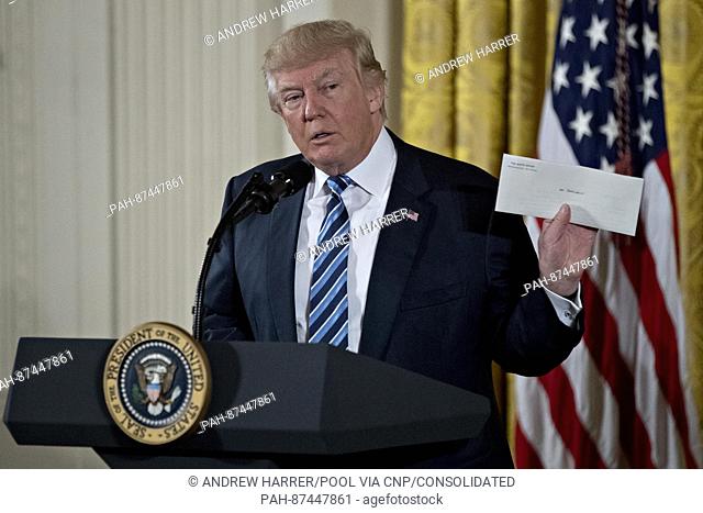 United States President Donald Trump holds up an envelope that was left for him in the Oval Office by former US President Barack Obama during a swearing in...