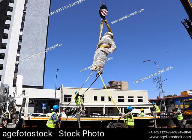 23 November 2022, Namibia, Windhuk: The statue of Curt von François is lifted from its pedestal by construction workers using a crane