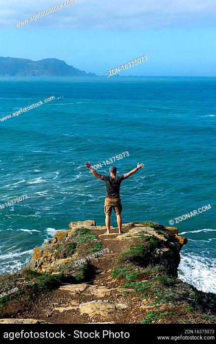 A man celebrating the view at the cliffs of Loiba in Galicia