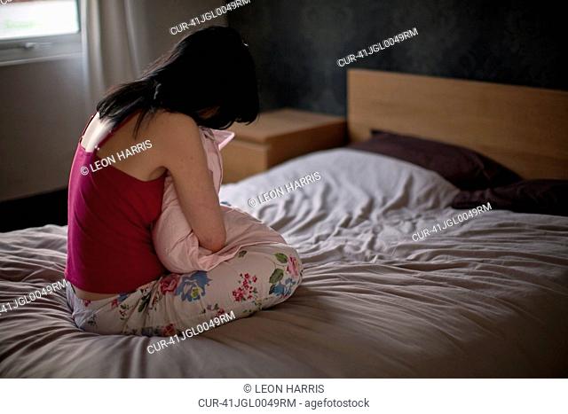 A young woman in bed, appearing depressed