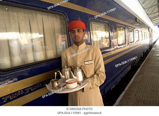 Rajasthani attendant holding tray of  beverage standing outside of Heritage on Wheels Journey into Past luxury tourist train ; Rajasthan ; India