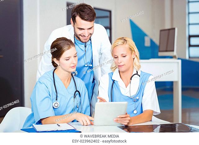 Female doctors using digital tablet while discussing with colleague