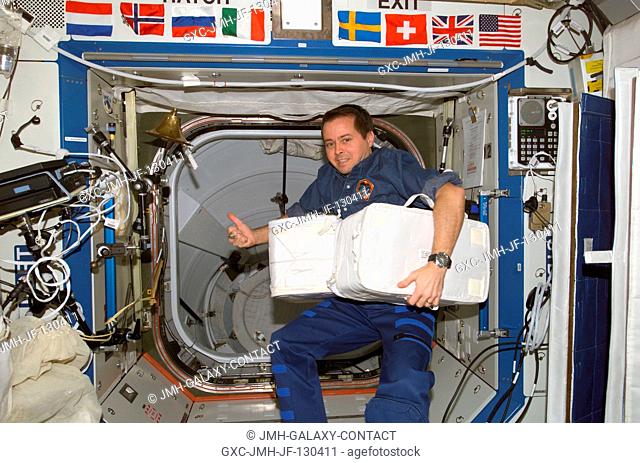 Astronaut Daniel W. Bursch, Expedition Four flight engineer, holds stowage containers in the Destiny laboratory on the International Space Station (ISS)