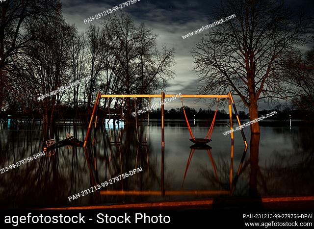 dpatop - 13 December 2023, North Rhine-Westphalia, Cologne: A swing frame in a playground stands in the flood waters of the Rhine
