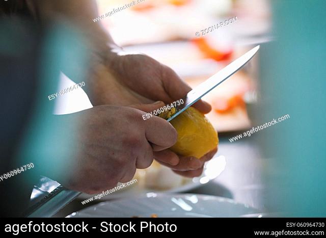 Chef is peeling potatoes for salad in commercial kitchen close-up