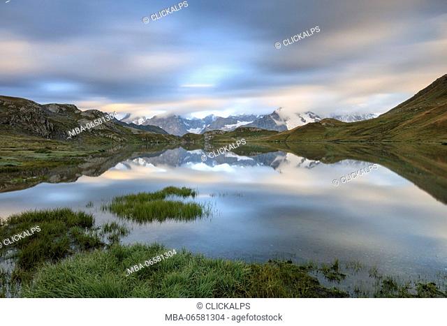 The snowy peaks are reflected in Fenetre Lakes at dawn Ferret Valley Saint Rhémy Grand St Bernard Aosta Valley Italy Europe