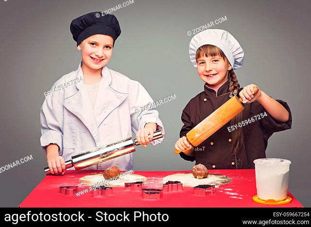 Beautiful boy and girl in chef clothes making christmas cookies with plunger over grey background. Copy space