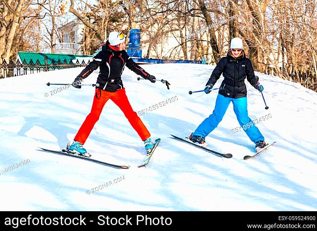 Samara, Russia - February 10, 2018: Young women in sport gear learns to ride skiing in sunny winter day