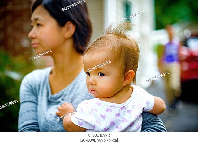 Mid adult woman carrying baby daughter in arms