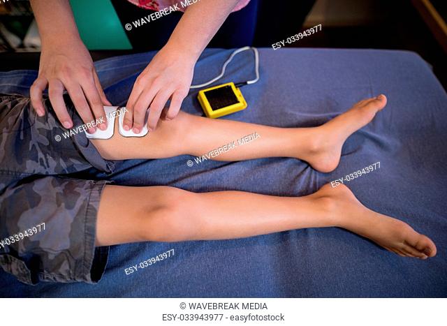 High angle view of female therapist placing electrodes on leg