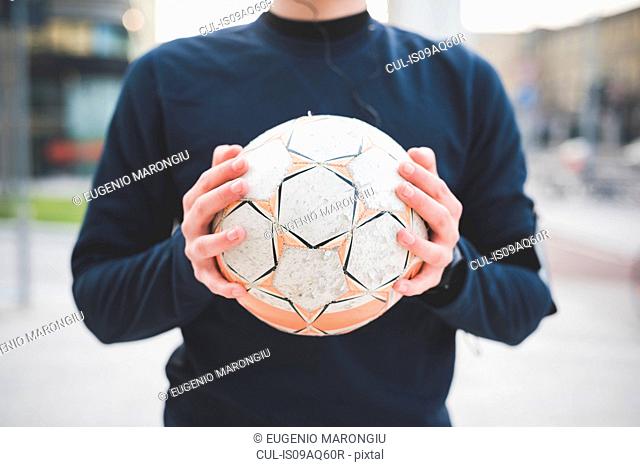 Cropped shot of young man holding soccer ball