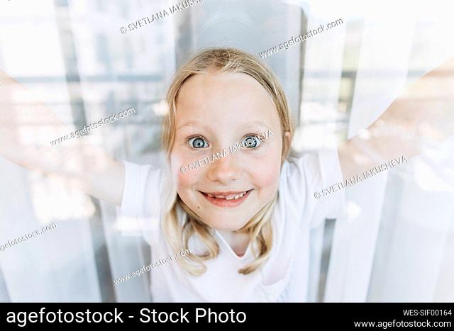 Happy girl making faces seen through window
