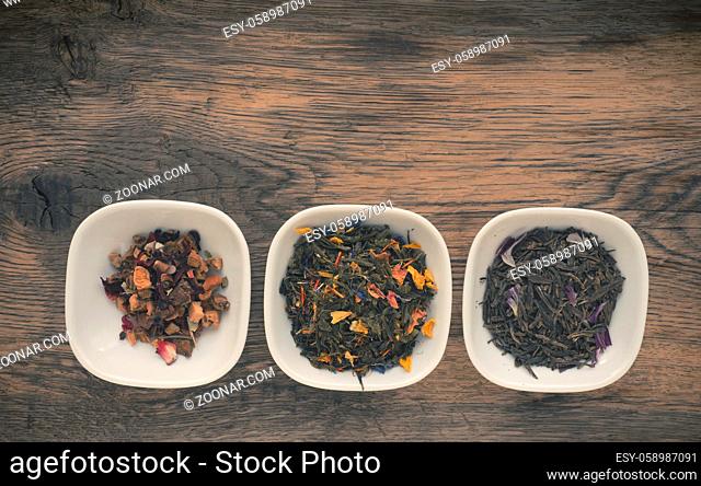 Assortment of tea in white bowls on a rustic wooden table