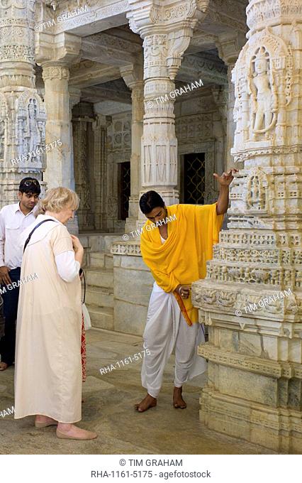 Temple priest shows tourists stone carving detail at The Ranakpur Jain Temple at Desuri Tehsil in Pali District of Rajasthan, India