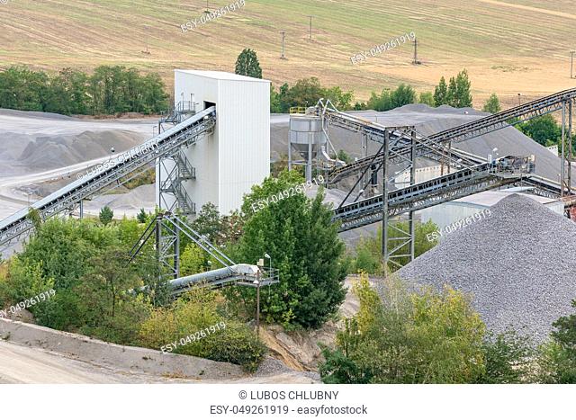 Mining quarry with machinery. Belt conveyors and mining equipment in a quarry. Stone quarry with silos, conveyor belts and piles of stones