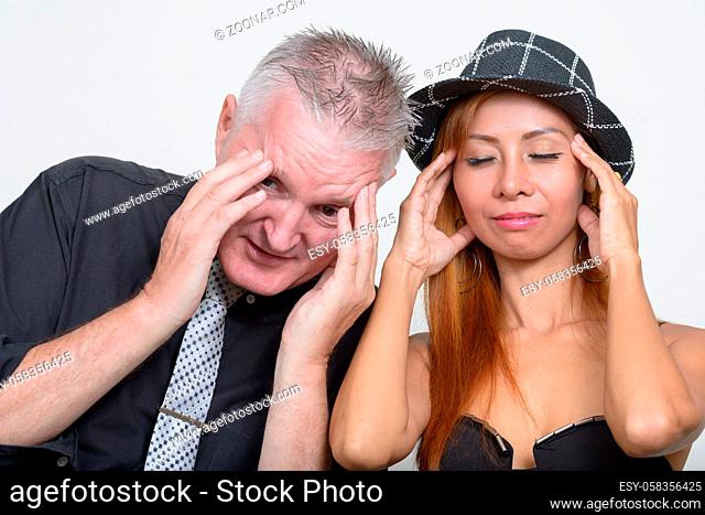Studio shot of senior man and mature Asian woman as couple together and in love against white background