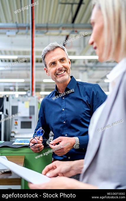 Smiling businessman and businesswoman talking in factory