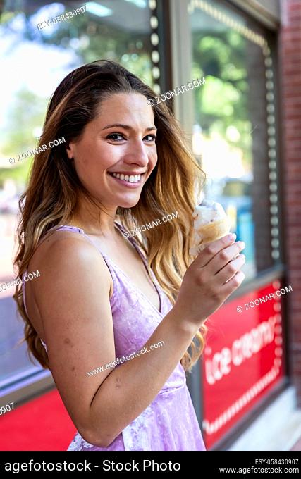 A beautiful Brunette model posing outdoors while eating ice cream in an urban environment