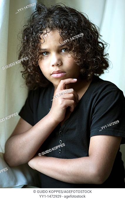 Tilburg, Netherlands. Studio-portrait of a young, dark-skinned teenager with curly hear
