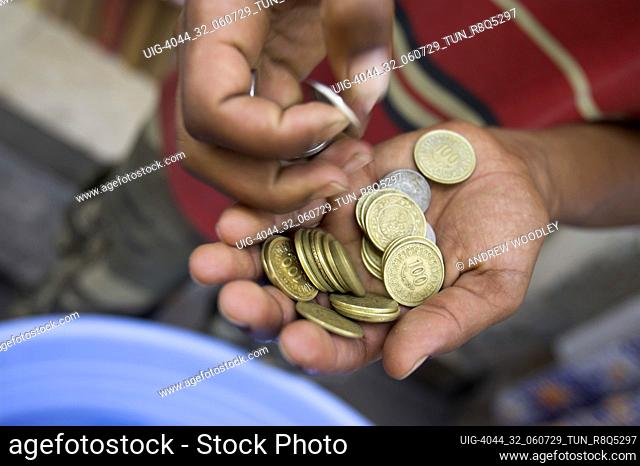 Street vendor counts Tunisian coins in the medina Tunis