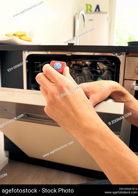 A middle-aged man equips a dishwasher with a cleaning tab, cleaning concept