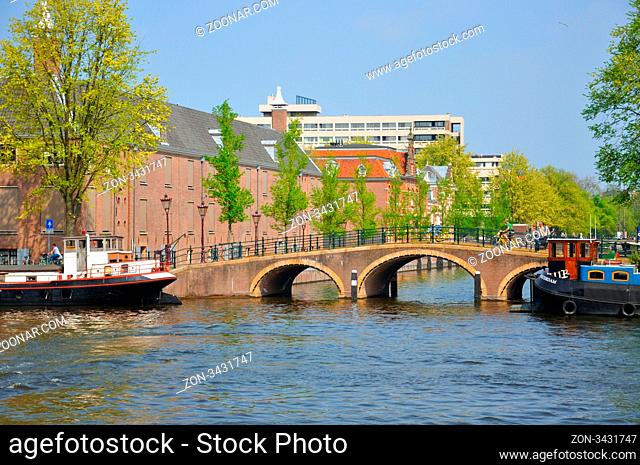Beautiful river with ships, Hermitage and Amstel bridge in Amsterdam, Holland (Netherlands)