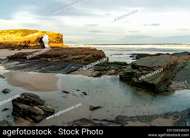 A beautiful beach with fine sand and rocky cliffs at sunrise
