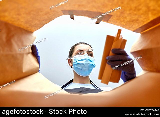 saleswoman in gloves and mask packing food in bag