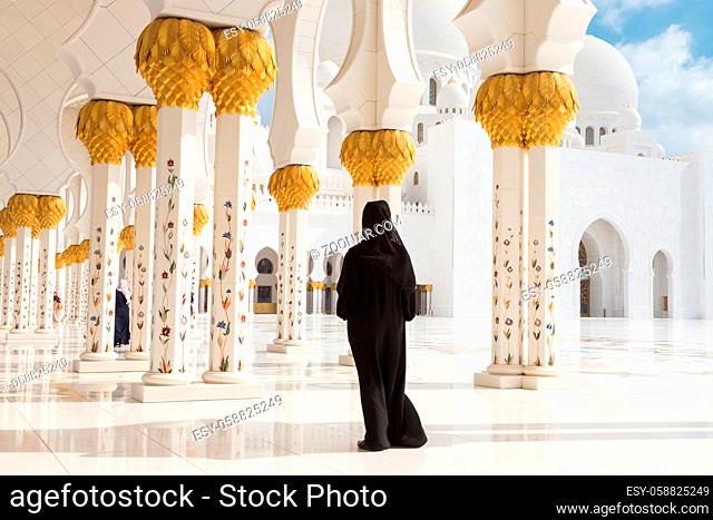 Traditionally dressed arabic woman wearing black burka wisiting Sheikh Zayed Grand Mosque in Abu Dhabi, United Arab Emirates