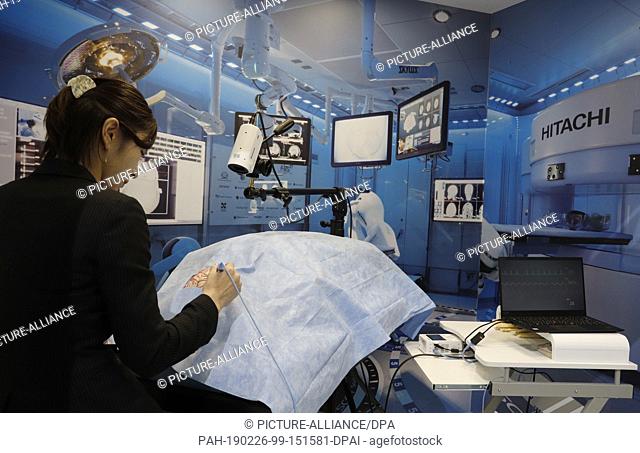 26 February 2019, Spain, Barcelona: At the Mobile World Congress 2019 in Barcelona, a woman demonstrates a digitized operating theatre at the NTT Docomo stand