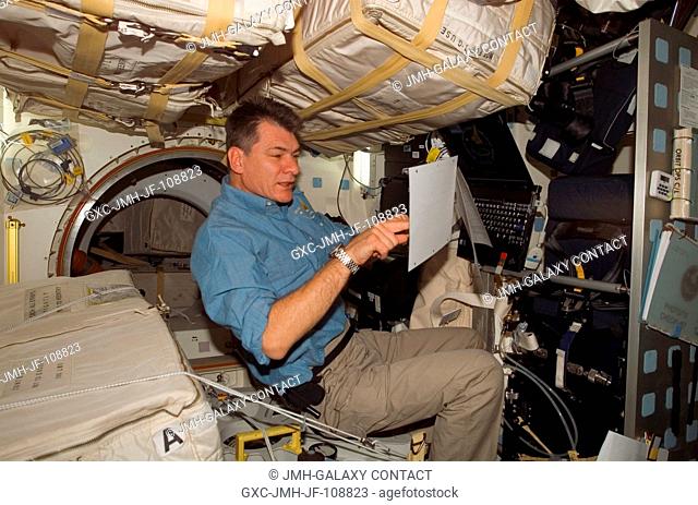 European Space Agency (ESA) astronaut Paolo Nespoli, STS-120 mission specialist, looks over procedures checklists on the middeck of Space Shuttle Discovery...