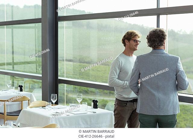 Men talking at winery dining room window