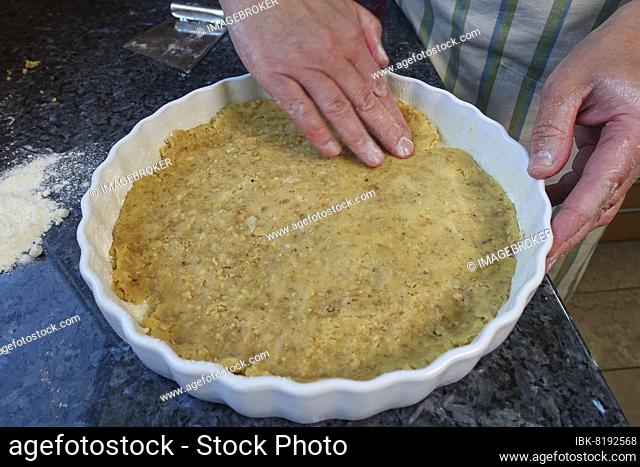 Southern German cuisine, baking, preparing hearty vegetable cake with walnut base, pressing walnut dough into the baking tin, tart tin, quiche tin