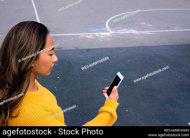 Woman on video call using smart phone at sports court