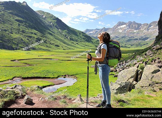 Side view full body portrait of a relaxed hiker breathing fresh air in a mountain valley