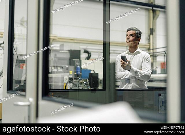 Mature businessman with cell phone in a factory
