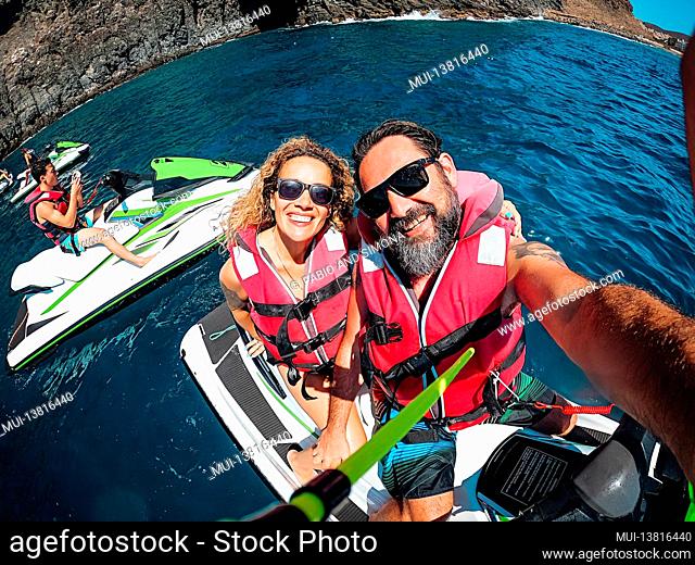 Group of tourists friends have fun with jet sky on the blue ocean water - happy couple enjoy freedom and sport activity together - summer travel holiday...