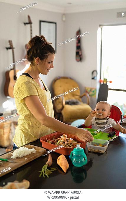 Mother feeding her baby in kitchen